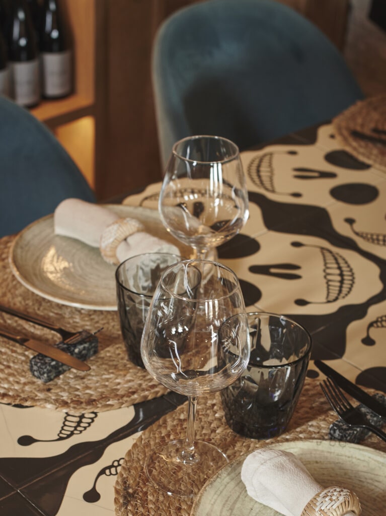 Mesa puesta con copas y mantel de calaveras